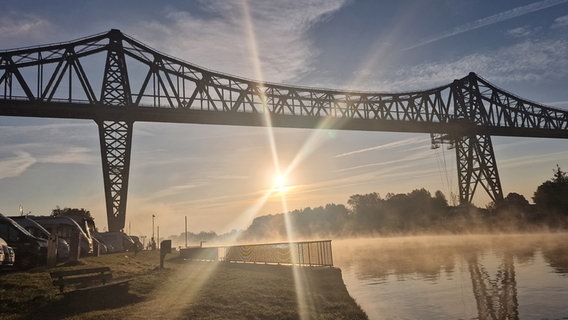 Die Sonne scheint zwischen den den Pfeilern der Rendsburger Eisenbahnhochbrücke hindurch. © Holger Gehrmann Foto: Holger Gehrmann