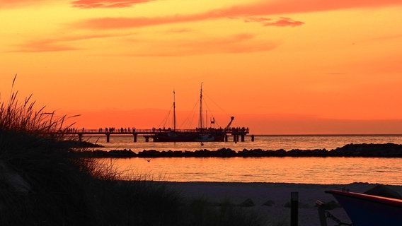 Ein Schiff liegt bei Sonnenuntergang vor dem Schönberger Strand im Wasser. © Susanne Kreding Foto: Susanne Kreding