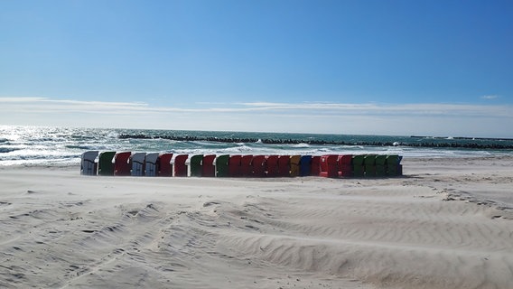 Mehrere bunte Strandkörbe stehen hintereinander aufgereiht. © Inken Schmidt Foto: Inken Schmidt