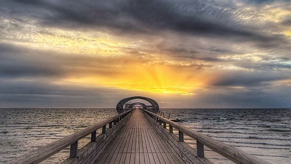 Blick auf den Sonnenaufgang über die Seebrücke Kellenhusen. © Mary Riedel Foto: Mary Riedel