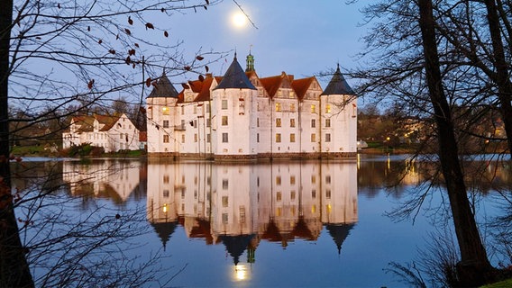 Das Glücksburger Schloss spiegelt sich bei Mondschein im Wasser. © Karl Kampmann Foto: Karl Kampmann