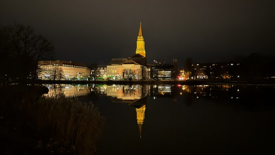 Blick bei Dunkelheit über den Kleinen Kiel auf das beleuchtete Rathaus und den Kieler Weihnachtsmarkt. © Michael Dumrese Foto: Michael Dumrese