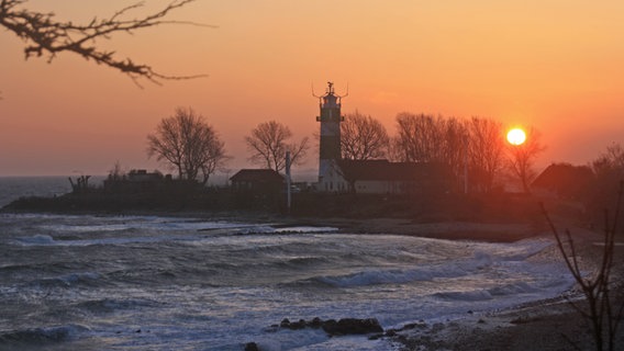 Am Bülker Leuchtturm mischt sich ein goldener Sonnenaufgang mit stürmischer See. © Katharina Troch Foto: Katharina Troch