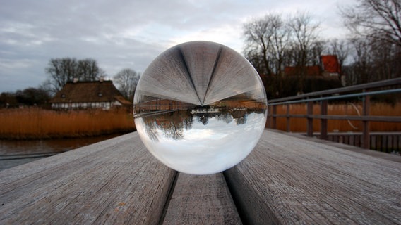 In einer Glaskugel spiegelt sich das alte Fährhaus von Sieseby. © Heike Greggersen Foto: Heike Greggersen