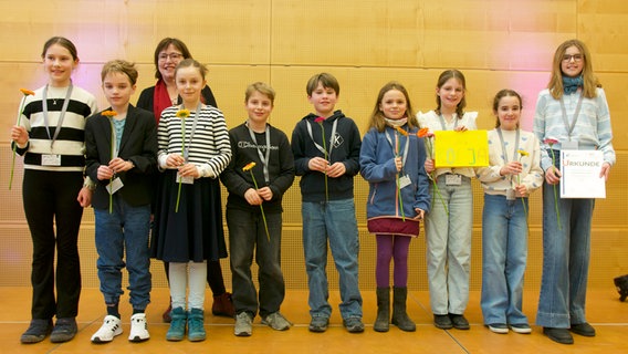 Anlässlich einer Auszeichnung ihrer Schülerzeitung erhalten junge Schüler und Schülerinnen Blumen und Urkunden. © Kaland Schule 