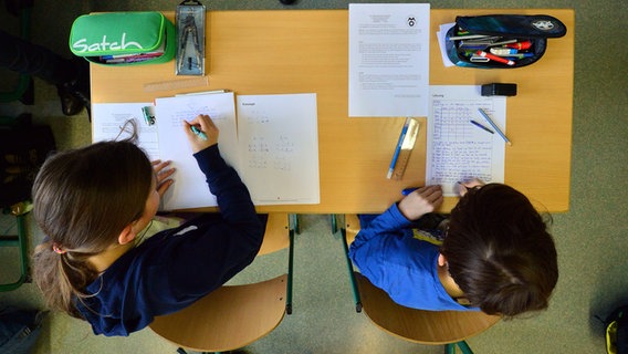 Zwei Schulkinder bearbeiten Aufgaben an einem Schultisch. © dpa-Zentralbild/dpa Foto: Martin Schutt