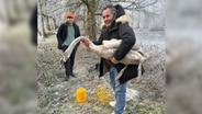 Antonio Saraiva hält einen geretteten Schwan im Arm. Im Hintergrund steht Leo Nizze. © Antonio Saraiva 