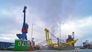 Mehrere Hafenkräne befinden sich auf einem Industriegelände in einem Hafen. © NDR Foto: Nils Hansen