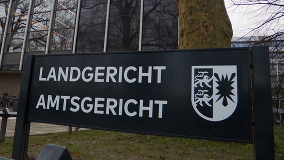 Ein schwarzes Schild mit dem Schriftzug "Landgericht Amtsgericht" steht vor dem Gebäude des Land- und Amtgerichts in Lübeck. © NDR 