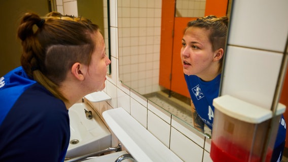 Eine Frau vor einem Spiegel in Handball-Trikot. © Tim Oehler Foto: Tim Oehler