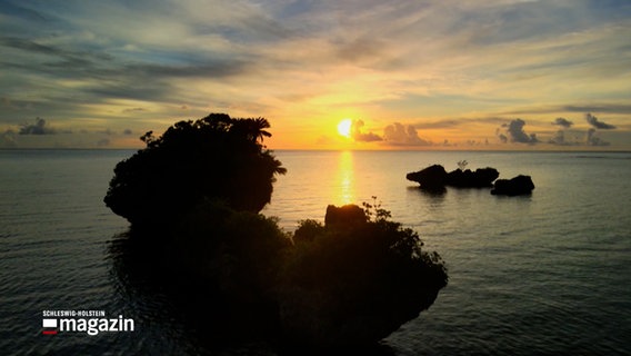 Hinter einer Insel steht die Sonne tief am Horizont © NDR Foto: NDR Screenshots