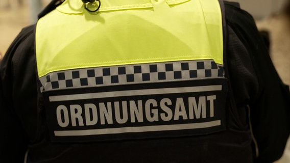 Auf der Rückseite einer Jacke einer Person steht "Ordnungsamt" © NDR Foto: NDR Screenshot