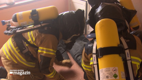 Drei Feuerwehrleute bei einer Übung © NDR Foto: NDR Screenshot