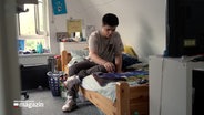 Ein junger Mann sitzt auf einem Bett © NDR Foto: NDR Screenshot