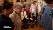 Eine Seniorin betrachte ein ihr präsentiertes Kleidungsstück © NDR Foto: NDR Screenshot