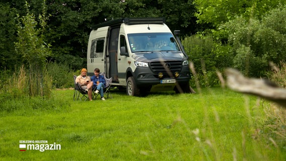 Zwei Personen sitzen in Klappstühlen vor einem Campingvan © NDR Foto: NDR Screenshot