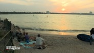 Menschen sitzen an einem Strand und betrachten einen Sonnenuntergang © NDR Foto: NDR Screenshot