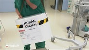 Eine Kiste mit der Aufschrift "Human Organ" wird in einen Operationssaal gebracht © NDR Foto: NDR Screenshot