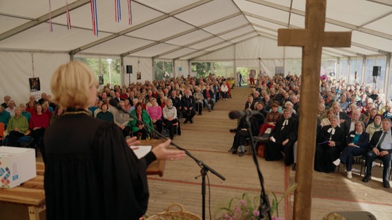 Der Blick von einem Altar in einem Zelt in dem eine Andacht zu einem Erntedankfest gehalten wird © NDR Foto: NDR Screenshot