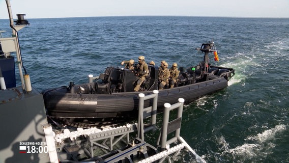 Ein aufblasbares Schnellboot auf dem Wasser, an Bord sind einige Personen in Tarnkleidung © NDR Foto: NDR Screenshot