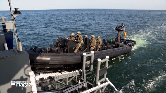 Ein aufblasbares Schnellboot auf dem Wasser, an Bord sind einige Personen in Tarnkleidung © NDR Foto: NDR Screenshot