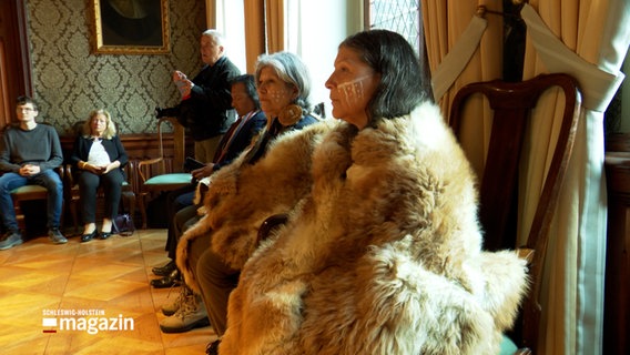 Einige mit Fell bekleidete Personen sitzen im Lübecker Rathaus © NDR Foto: NDR Screenshot