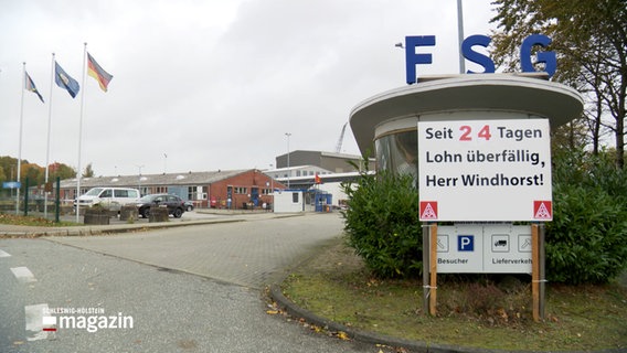 Der Eingang zur FSG-Werft in Flensburg, davor ein Schild mit der Aufschrift: "Seit 24 Tagen Lohn überfällig, Herr Windhorst!" © NDR Foto: Tobias Gellert