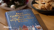 Eine Buch mit dem Titel "Das Geheimnis der Weihnachtskiste" liegt auf einem Tisch © NDR Foto: NDR Screenshot