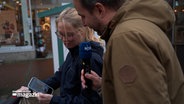 Eine Frau zeigt Reporter Hauke Bülow ein Foto auf ihrem Handy. © NDR Foto: NDR Screenshot