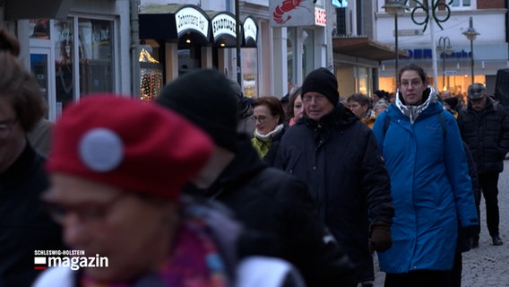 Menschen gehen durch eine Fußgängerzone von Husum als Erinnerung an Häftlingsmärsche zu Zeiten den dritten Reiches © NDR Foto: NDR Screenshot