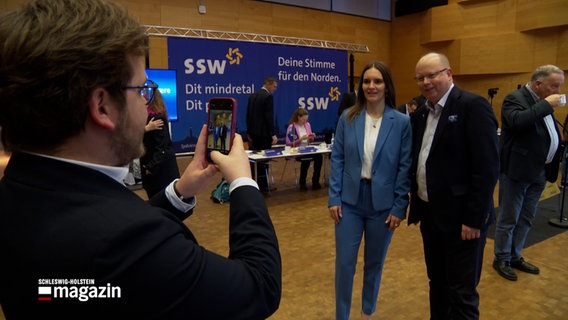 Der SSW-Spitzenkandidat Stefan Seidler und seine Parteikollegen Maylis Roßberg posieren für ein Foto auf einem Parteitag © NDR Foto: NDR Screenshot