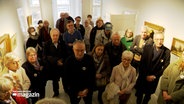 Mehrere Menschen stehen bei einer Führung in einem Museum gedrängt zusammen © NDR Foto: NDR Screenshot