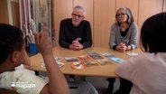 Schüler einer Grundschule im Gespräch mit zwei Senioren in einem Klassenzimmer © NDR Foto: NDR Screenshot