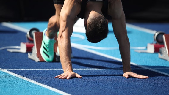 Ein Mann bringt sich in Position für einen Sprintlauf. © picture alliance Foto: Maximilian Koch