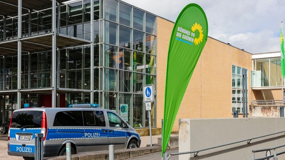 Blick auf ein Polizeiauto und eine Fahne der Grünen vor der Stadthalle Neumünster. © picture alliance/dpa | Frank Molter Foto: Frank Molter