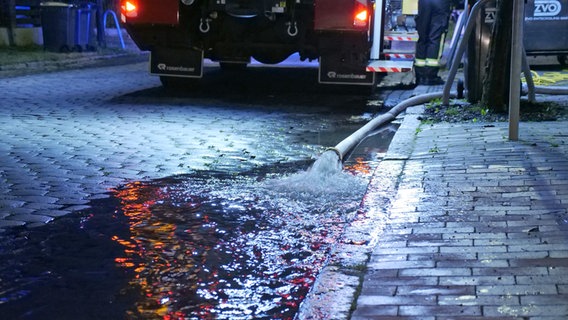 Nach heftigen Regenfällen strömt Wasser aus einem Feuerwehrschlauch auf eine Straße in Eutin. © Daniel Friedrichs Foto: Daniel Friedrichs