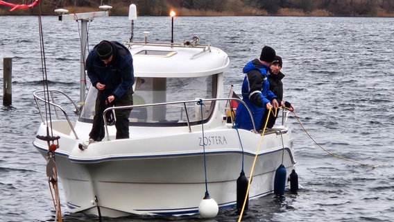 Drei Menschen stehen an Deck eines Forschungsschiffs, das über den Großen Segeberger See fährt. © NDR Foto: Johannes Tran