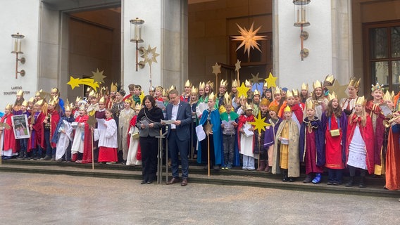 Landtagspräsidentin Kristina Herbst (CDU) und Ministerpräsident Daniel Günther (CDU) stehen zusammen mit einer Gruppe Sternsinger vor dem Landeshaus. © NDR Foto: Anna Grusnick