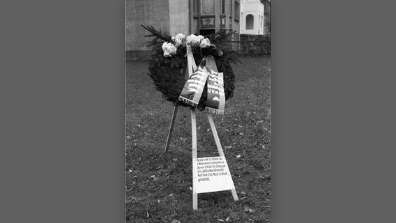 Eine historische Aufnahme zeigt eine Gedenktafel mit einem Kranz auf einem Rasen stehen. © Stadtarchiv Kiel/Gesellschaft für Kieler Stadtgeschichte 