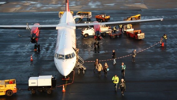 Passagiere verlassen ein Flugzeug auf der Landebahn des Flughafens auf Sylt. © NDR Foto: Simone Steinhardt