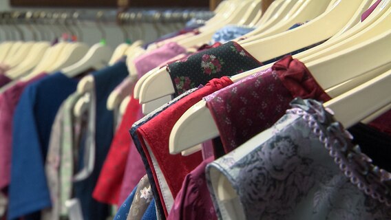 Traditional costumes hang on the hangers in Ankes Trachtengalerie in Linau.  © NDR 