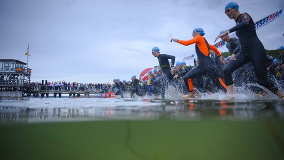 Teilnehmer des Triathlon Glücksburg laufen ins Wasser. © Ostseeman 