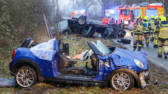 Ein schwer beschädigtes blaues Fahrzeug steht am Straßenrand bei Pinneberg, dahinter liegt ein zweites schwarzes Fahrzeug auf dem Dach nach einem frontalen Zusammenstoß. © Florian Sprenger Foto: Florian Sprenger