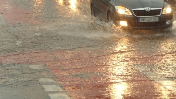 Ein Auto fährt über eine leicht überschwemmte Straße. © Daniel Friedrichs Foto: Daniel Friedrichs