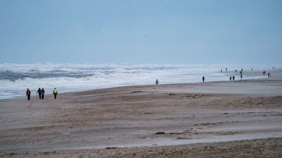 Spaziergänger gehen am Strand von Westerland entlang Foto: Axel Heimken