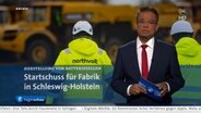 Tagesschau24-Moderator Michail Paweletz steht im Studio und berichtet über den Baubeginn der Northvolt-Fabrik bei Heide © ARD Foto: ARD Screenshot