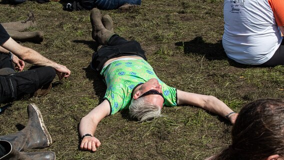 Eine Person liegt im Schlamm des Wacken Open Air. © NDR Foto: Christoph Klipp