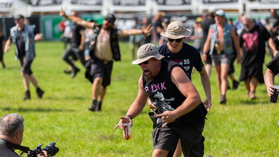 Menschen rennen jubelnd auf ein Festivalgelände. © NDR Foto: Dominik Dührsen