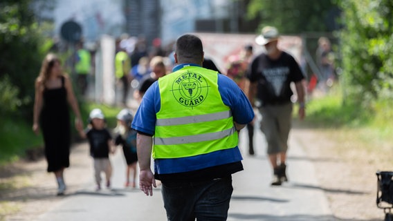 Ein Mann in grüner Warnweste geht eine Straße entlang. © NDR Foto: Dominik Dührsen