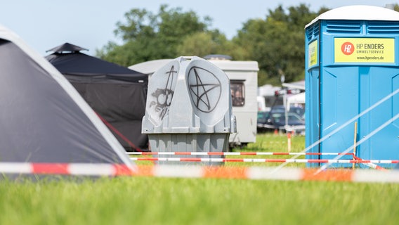 Ein Urinal steht auf einem Campingplatz zwischen einem Zelt und einem Dixi-Klo. © NDR Foto: Dominik Dührsen